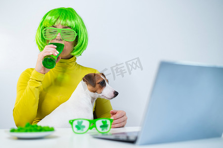一位戴着绿色假发和欢快眼镜的年轻女子喝着啤酒，咬着釉面坚果。
