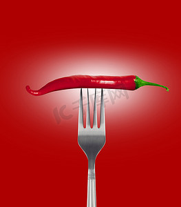 红辣椒刺到红色背景上的金属叉上