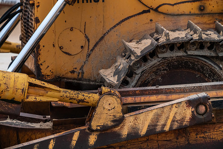 芝加哥海滩上一台旧的大型工业黄色推土机履带的特写照片，风化、生锈和磨损。