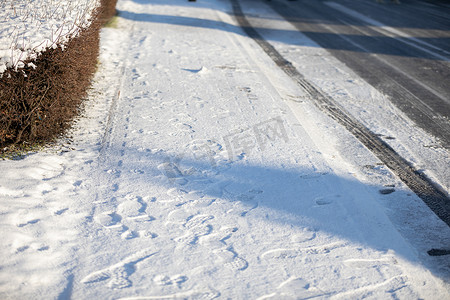 轮胎轨迹轮胎摄影照片_卢布林居民区人行道和街道上未经处理的冻雪。
