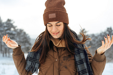 穿着冬季保暖夹克的女人在白雪皑皑的冬季森林中行走