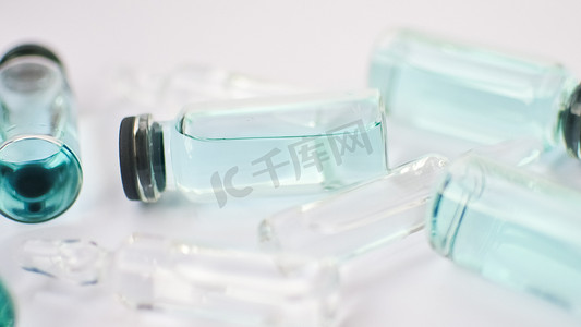 小瓶疫苗，白色背景上透明和蓝色液体的玻璃安瓿顶视图，全球疫苗接种概念