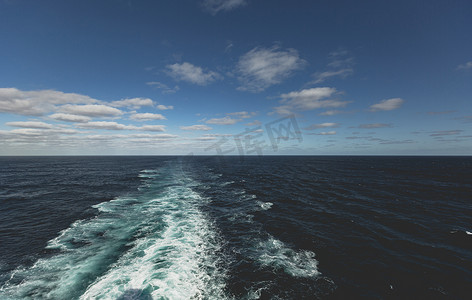 浩瀚船舶摄影照片_在明亮的阳光下航行穿过海洋时船后的波浪