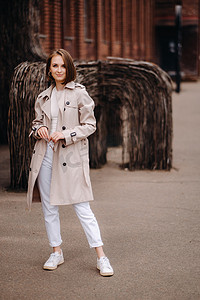 一个穿着灰色外套的快乐时尚女孩在城市里走来走去