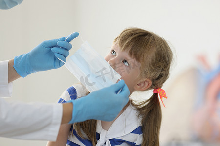 医生在孩子脸上戴上口罩以防止病毒传播