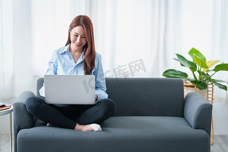 社交内容摄影照片_女人喜欢坐在家里沙发上的笔记本电脑上观看内容流媒体电影或社交媒体应用程序。