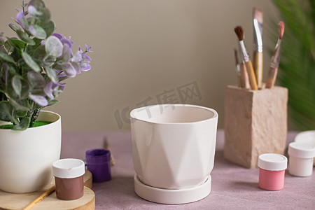 一张白色陶瓷花盆的静物画站在紫色牛皮纸上的桌子上