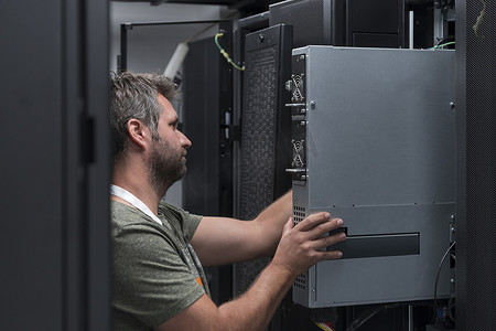 在服务器机房或数据中心工作的 IT 工程师技术人员将公司业务大型机超级计算机或 cryptocurrency 采矿场的新服务器放在机架中。