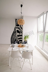 简元素摄影照片_简约风格的轻型餐厅的室内设计，配有方形木制服务器白桌、黑白椅子，枝形吊灯和桌子上有柳条装饰。