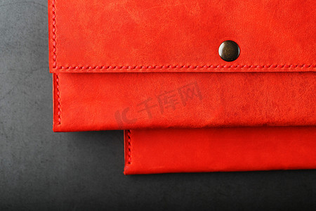 一对红色真皮钱包，深色背景顶视图上有铆钉。