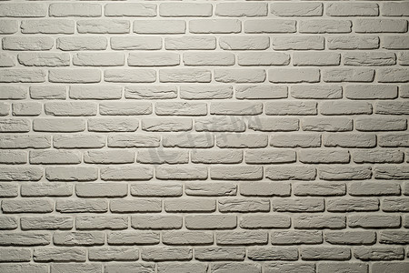 白色砖墙摄影照片_一盏灯从上方照亮了暖色调的白色砖墙。