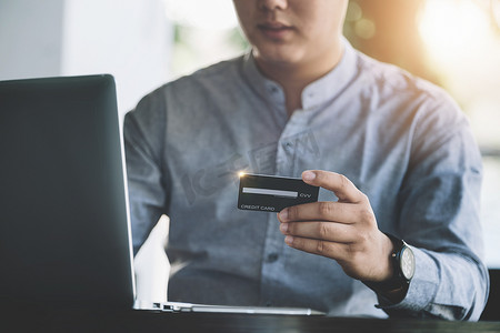 网上购物和互联网支付，亚洲男性正在使用信用卡和笔记本电脑在网上购物或在数字世界中办事。