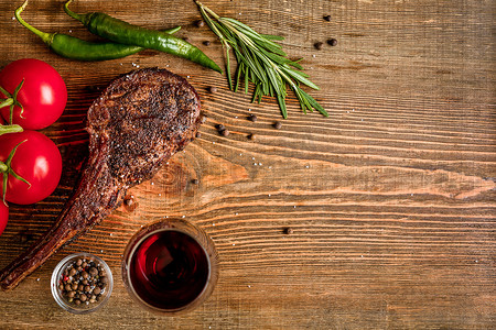 木制背景中特写的烧烤干牛肉肋骨、蔬菜和红酒杯