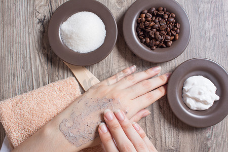 黑金磨砂质感摄影照片_一位女士在皮肤上涂抹天然咖啡磨砂膏。