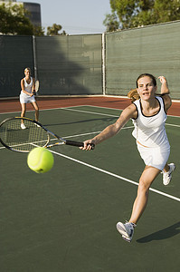 女网球运动员与站在背景中的搭档一起击球