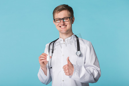药物和药物概念 — 蓝色背景中竖起大拇指的男医生或药剂师拿着鼻腔喷雾剂