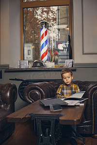 小男孩在理发店，在候诊室等着师父。
