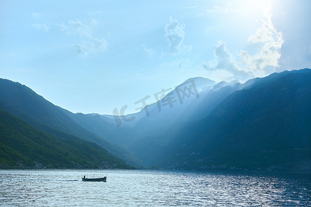 黑山山背景下，一艘载着渔民的船漂浮在海上