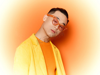 身穿橙色背景黄色毛衣、脸上戴着眼镜、亚洲外观的时尚男士