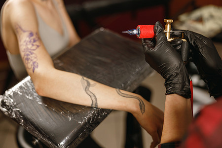纹身师手戴黑手套打开纹身机的照片