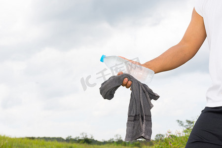 手里拿着水瓶和毛巾的男人和自然背景视图。