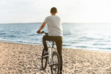 自行车站在城市沙滩上的年轻男子。