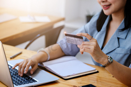 在线购物和互联网支付，美丽的亚洲女性正在使用信用卡和笔记本电脑在数字世界中在线购物或办事