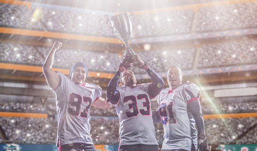 美式足球队在杯赛决赛中拿着奖杯庆祝胜利