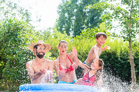 花园游泳池摄影照片_家庭在花园游泳池里泼水降温