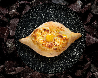 Adjarian georgian khachapuri 在石头背景的黑盘上放着鸡蛋和奶酪民族传统美食