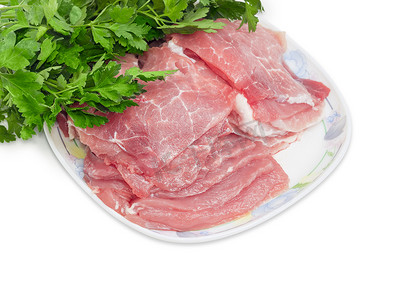 冷冻摄影照片_欧芹背景下，菜上切成片的生猪肉