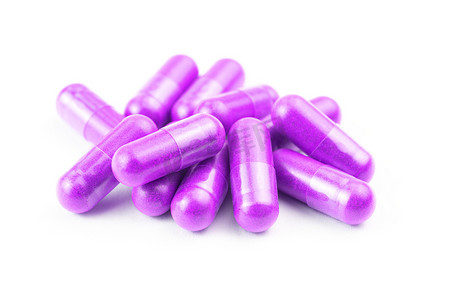 一堆质子紫色有机胶囊隔离在白色背景特写上，有选择的焦点