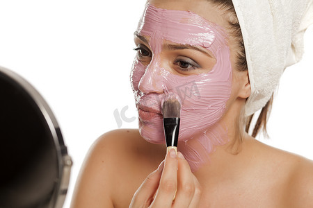 女人在脸上敷面膜，头上戴着毛巾
