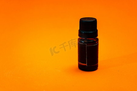 包装瓶样机摄影照片_橙色背景上绝缘的小琥珀色玻璃滴管瓶。