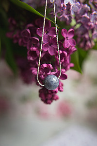 天然石材制成的项链，配有银色配件，白色鸵鸟羽毛上饰有紫色紫丁香花。