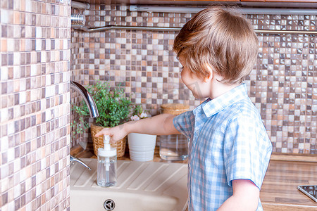 小男孩在带植物的棕色木制厨房水槽中洗手
