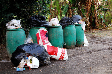 回收垃圾箱摄影照片_垃圾箱、垃圾箱和地面上的许多垃圾袋、回收垃圾的垃圾箱废塑料、垃圾很多、村里的污染垃圾