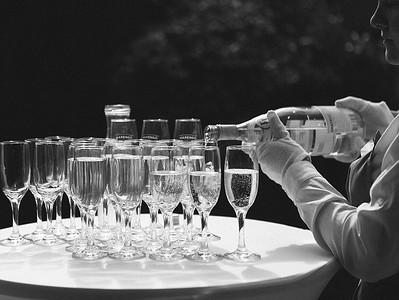在庆祝的气氛中倒香槟祝酒，在金色的薄片散景颗粒效果上放上香槟杯