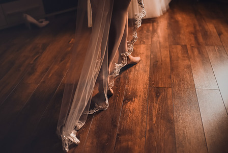新娘穿着白色丝袜的双腿沿着棕色木镶木地板行走