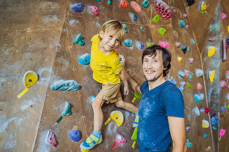 爸爸和孩子运动摄影照片_爸爸和儿子在攀岩墙。