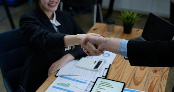 两个商务人士一起接受商业建议后握手，握手是一种普遍的敬意，常用于问候或祝贺。