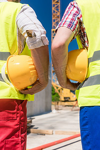 两名戴着黄色安全帽的工人手的背面图