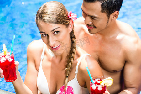 亚洲酒店泳池里的情侣喝鸡尾酒