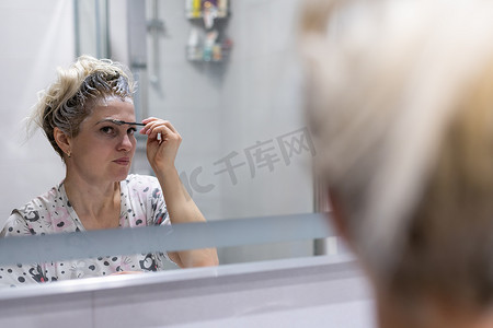 女性眉毛摄影照片_女人自己染头发和眉毛