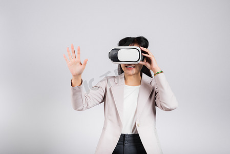微笑的女性自信兴奋地佩戴 VR 耳机设备在虚拟现实体验中触摸空气