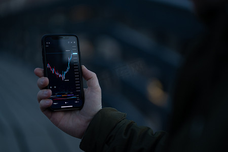 商人或交易员在手机屏幕上分析外汇图表和财务数据