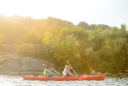 年轻快乐的夫妇在美丽的河流或湖泊上划皮划艇