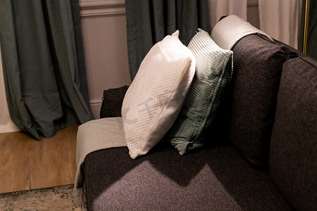 舒适的枕头套，枕套采用不同材料和质地的纺织品。沙发装饰上的舒适枕头。室内配有带白色床单和彩色枕头的床。