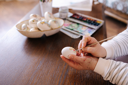 复活节彩蛋水彩摄影照片_为复活节彩蛋节在幻想鸡蛋上画水彩的女人。