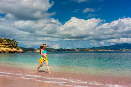 在热带海滩上享受幸福和自由的时尚年轻女性